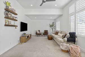 Carpeted living room with ceiling fan