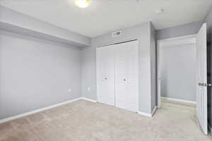 2nd bedroom featuring light colored carpet and a closet and natural light