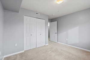 2nd bedroom featuring light colored carpet and a closet and natural light