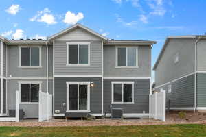 Back of house featuring a lawn and central AC unit