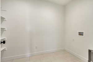 Laundry area with light tile patterned floors, laundry area, hookup for a washing machine, and baseboards