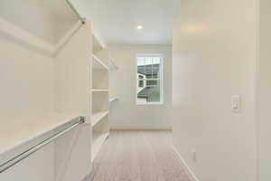 Walk in closet with light colored carpet