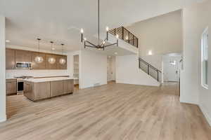 Kitchen with decorative light fixtures, stainless steel appliances, light hardwood / wood-style floors, and a kitchen island