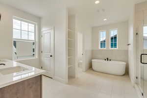 Full bathroom with shower with separate bathtub, tile walls, vanity, and toilet