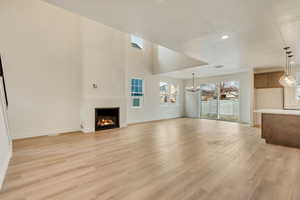 Unfurnished living room featuring an inviting chandelier and light hardwood / wood-style flooring