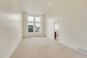 Unfurnished room with light colored carpet and a high ceiling