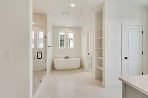 Bathroom with recessed lighting, a freestanding bath, a shower stall, vanity, and tile patterned flooring