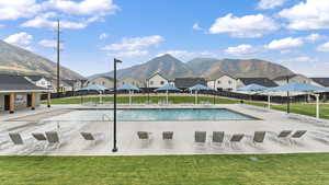 View of swimming pool with a mountain view, a patio area, and a yard