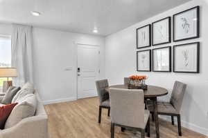 Dining area with a textured ceiling and light wood-type flooring