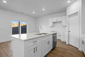 Kitchen featuring dishwasher, a center island with sink, sink, dark hardwood / wood-style flooring, and white cabinetry