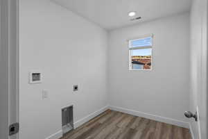 Clothes washing area with hookup for an electric dryer, hardwood / wood-style floors, and washer hookup