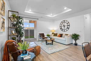 Living room with a tray ceiling and light wood-type flooring