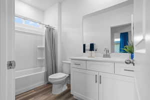 Full bathroom with wood-type flooring, vanity, toilet, and shower / bathtub combination with curtain