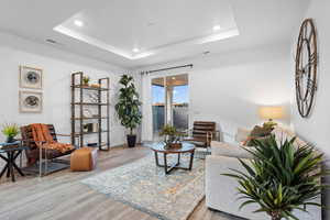 Living room featuring a raised ceiling and light wood-type flooring