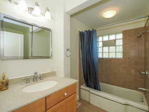 Bathroom featuring tile patterned floors, vanity, and shower / bathtub combination with curtain