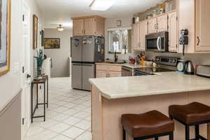 Kitchen featuring a kitchen breakfast bar, kitchen peninsula, light brown cabinets, and appliances with stainless steel finishes