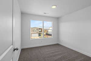 Carpeted spare room featuring a textured ceiling