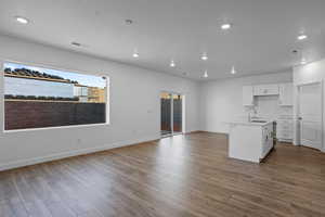 Kitchen with a kitchen island with sink, light hardwood / wood-style flooring, white cabinets, and sink