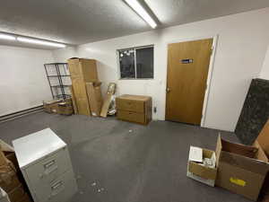 Basement featuring a textured ceiling and baseboard heating