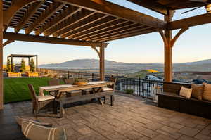 Patio terrace at dusk featuring a mountain view, a yard, a pergola, and an outdoor hangout area