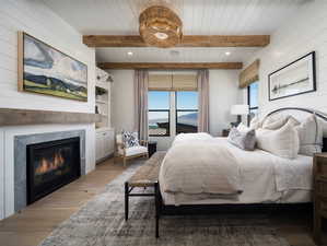 Bedroom featuring beam ceiling, wooden walls, light hardwood / wood-style flooring, and wood ceiling