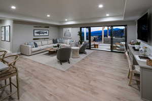 Living room with a raised ceiling and light hardwood / wood-style flooring