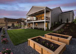 Back house at dusk featuring a pergola, a balcony, a patio, cooling unit, and a yard