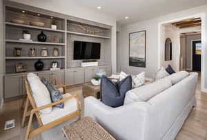 Living room with built in shelves and light wood-type flooring