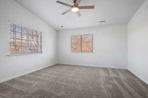 Spare room with carpet flooring, ceiling fan, and vaulted ceiling