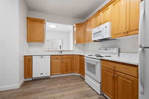 Kitchen with sink, white appliances, and hardwood / wood-style flooring