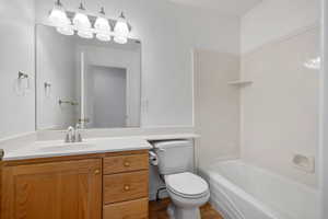 Full bathroom with bathing tub / shower combination, hardwood / wood-style flooring, vanity, and toilet