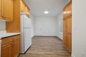 Kitchen with white fridge and light hardwood / wood-style flooring