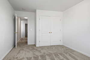 Unfurnished bedroom featuring light colored carpet and a closet