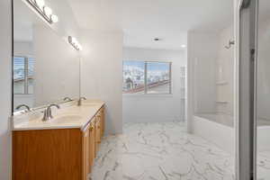 Bathroom featuring vanity, shower / bath combination, and a wealth of natural light