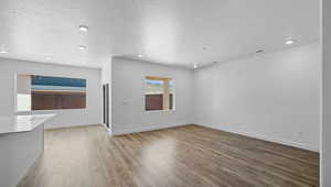 Unfurnished living room featuring hardwood / wood-style floors and a textured ceiling