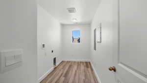 Washroom featuring electric dryer hookup, light hardwood / wood-style floors, a textured ceiling, and hookup for a washing machine