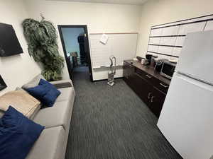 Interior space featuring dark colored carpet, dark brown cabinets, and white refrigerator