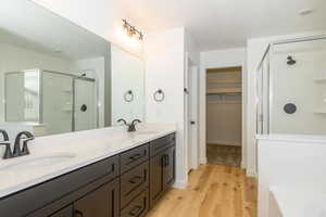 Bathroom with vanity, wood-type flooring, a shower with shower door, and a textured ceiling