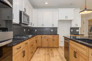 Kitchen with white cabinets, decorative light fixtures, stainless steel appliances, and sink