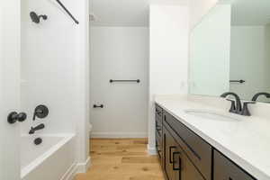 Full bathroom with vanity, shower / bathtub combination, toilet, and wood-type flooring