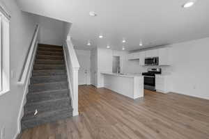 Kitchen featuring white cabinets, sink, appliances with stainless steel finishes, light hardwood / wood-style floors, and kitchen peninsula