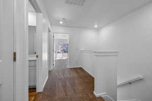 Hallway featuring a textured ceiling and dark carpet