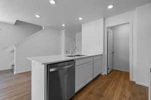 Kitchen featuring dishwasher, dark hardwood / wood-style floors, white cabinetry, and sink