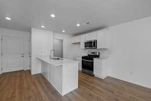 Kitchen with sink, a textured ceiling, white cabinetry, kitchen peninsula, and stainless steel appliances