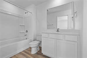 Full bathroom with bathtub / shower combination, wood-type flooring, vanity, and toilet