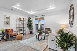 Living room featuring a tray ceiling and light hardwood / wood-style flooring