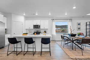 Kitchen with white cabinets, appliances with stainless steel finishes, sink, and an island with sink