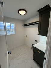 Laundry room with hookup for an electric dryer, cabinets, and washer hookup