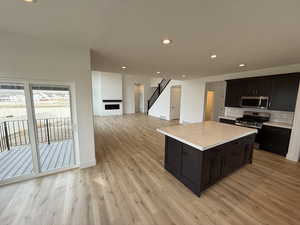 Kitchen featuring tasteful backsplash, a kitchen island, appliances with stainless steel finishes, and light hardwood / wood-style floors