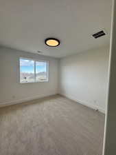 Spare room featuring light colored carpet and a textured ceiling